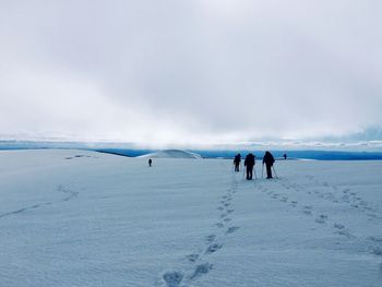 Rear view of people on snowcapped landscape against sky