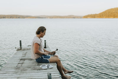 Man sitting on jetty and using laptop