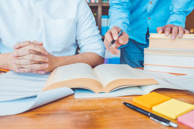 Midsection of woman reading book on table
