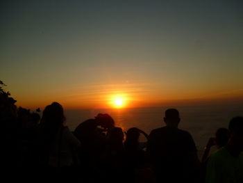 Silhouette people standing against sky during sunset