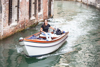 Man sitting in boat against canal