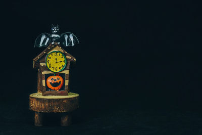 Close-up of clock on table against black background