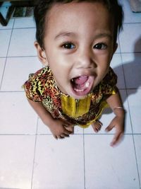 Portrait of cute baby girl on tiled floor at home