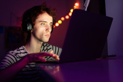 Man using laptop while sitting in darkroom