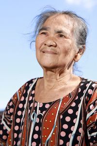 Low angle view of young woman standing against clear sky