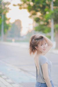 Rear view portrait of sensuous young woman standing on footpath