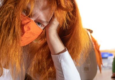 A red-haired woman is wearing a medical respirator, she is exhausted