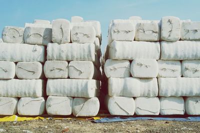 Stack of covered hay bales on field against sky