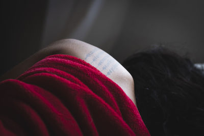 Close-up of woman with tattoo on shoulder sleeping at home