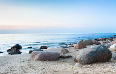 Rocks on beach against sky during sunset