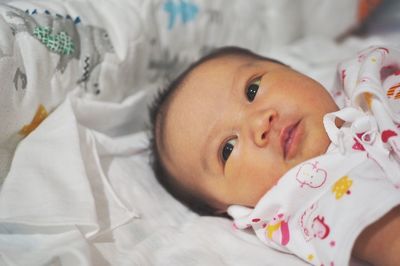 Portrait of cute baby lying on bed