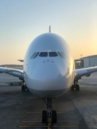 Airplane on runway against sky during sunset