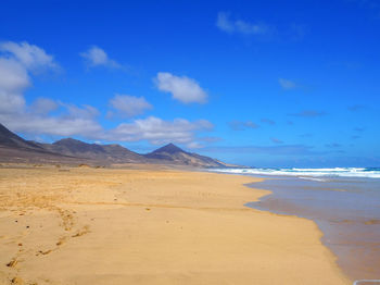 Scenic view of beach against blue sky