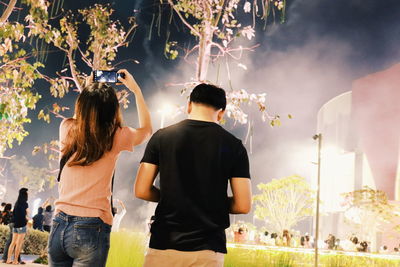 Rear view of people standing against trees