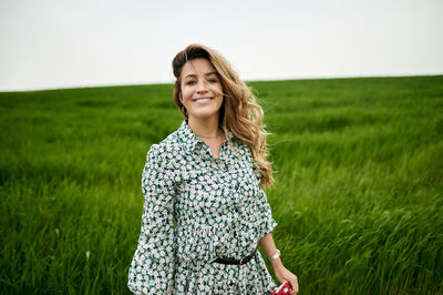 Portrait of smiling young woman standing on field