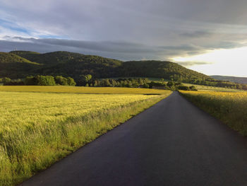 View of country road against cloudy sky