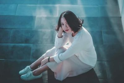 High angle portrait of beautiful woman sitting on floor outdoors