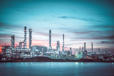 Illuminated factory against sky at dusk