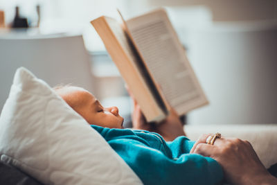 Cropped image of parent with baby sleeping on bed