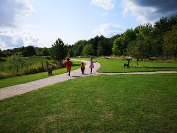 People walking on footpath in park against sky