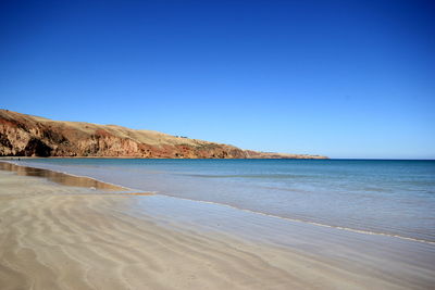 View of calm beach against clear blue sky