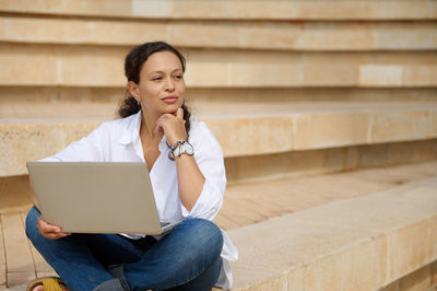 Young businesswoman using laptop while sitting on staircase