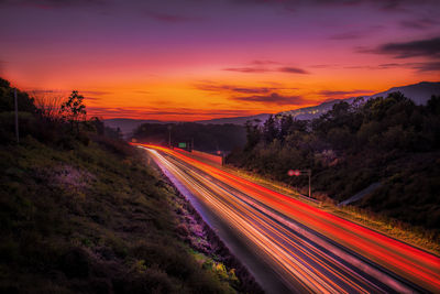Light trails on road against sky during sunset