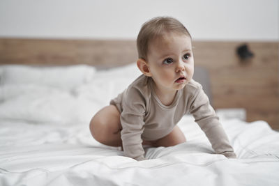 Baby girl lying sitting on bed at home