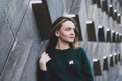 Portrait of beautiful young woman standing against wall