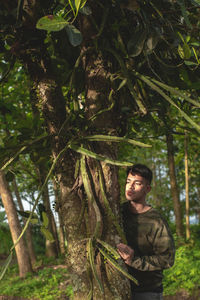 A man standing behind a tree with leptocereus quadricostatus plants on it