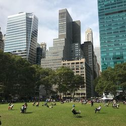 People on modern buildings in city against sky