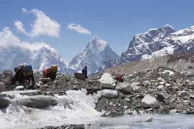 People and animals against mountains during winter