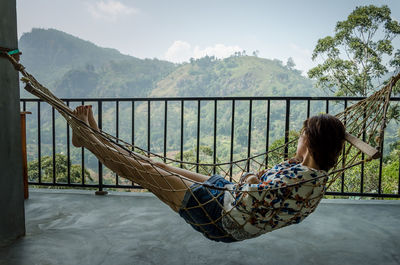 Woman relaxing in hammock at balcony