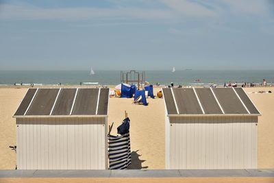 Hooded chairs on beach against sky