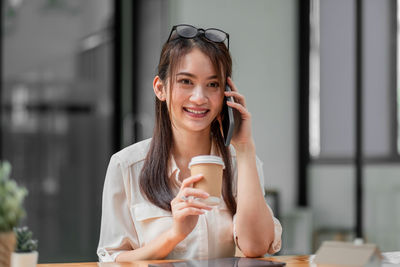 Portrait of a smiling young woman drinking coffee