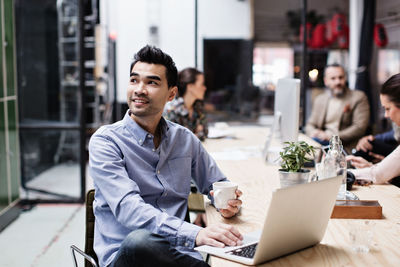 Young man using laptop while sitting on table