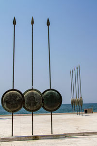 Row of street light by sea against clear blue sky