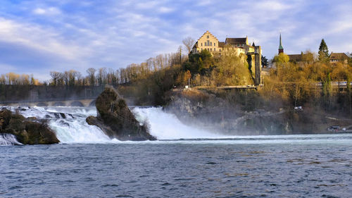 Scenic view of waterfall by sea against sky