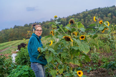 Full length of smiling young woman with yellow flowers on field