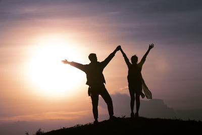 Silhouette people standing against sky during sunset