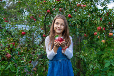 Portrait of smiling young woman blowing flowers