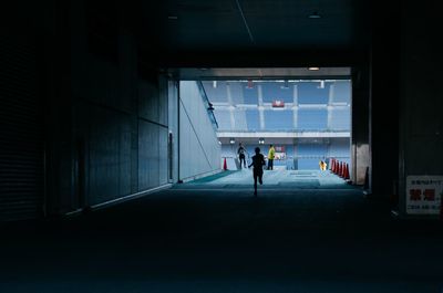 Silhouette person running on walkway of building