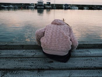 Rear view of person sitting next to river