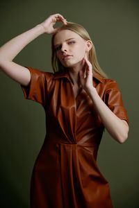 Portrait of young woman standing against yellow wall