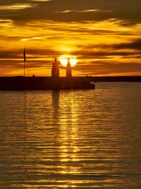 Silhouette boat in sea against orange sky