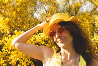 Portrait of young woman wearing hat standing against trees