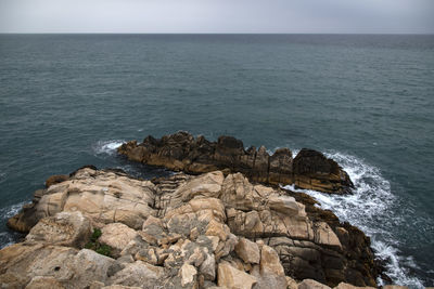 Rocks on sea shore against sky