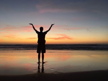 Silhouette woman standing at beach during sunset