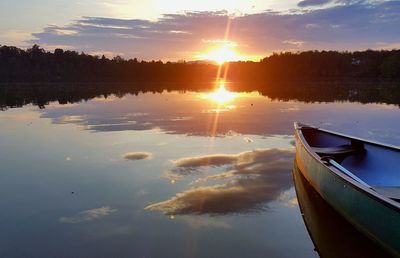 Boat moored on lake against sky during sunset