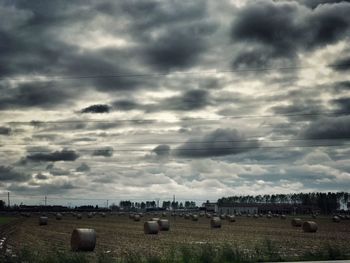 Hay bales on field against sky